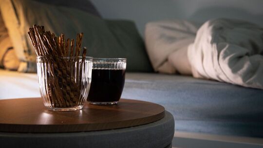 Aufgeschlagenes Bett mit Salzstangen und Cola