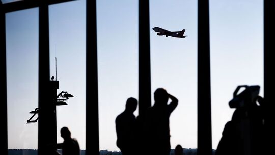 Passagiere schauen am Flughafen einem startenden Flugzeug zu