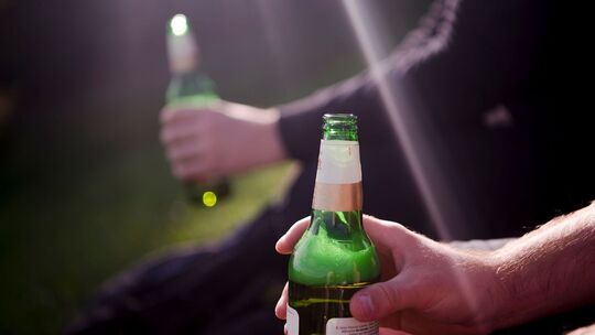 Zwei Männer sitzen im Olympia-Park und trinken Bier