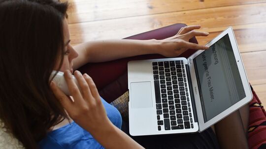 Frau mit Laptop telefoniert