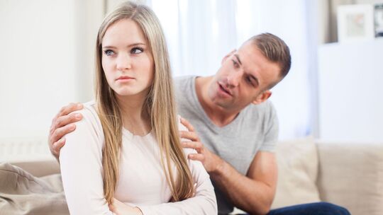 Frau sitzt enttäuscht neben ihrem Partner