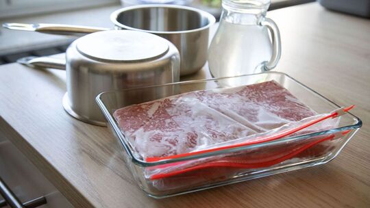 Tiefgefrorenes Hackfleisch liegt neben zwei Töpfen