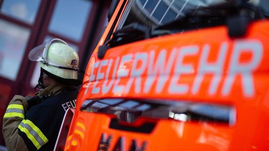 Feuerwehrmann steht neben einem Feuerwehrauto (Symbolbild)