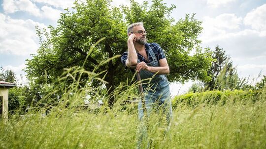 Ein Mann steht mit einem Spaten im Garten