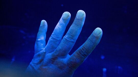 Desinfizierte Hand wird unter eine UV-Lampe gehalten
