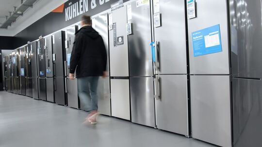 Mann geht im Elektronikmarkt an Kühl-Gefrierkombinationen vorbei