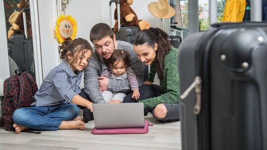 Familie plant mit Laptop ihren Urlaub