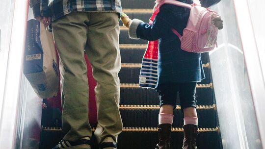 Mädchen steht neben ihrem Vater auf einer Rolltreppe
