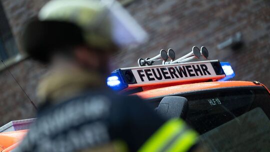 Einsatzkraft der Feuerwehr steht vor einem Einsatzfahrzeug
