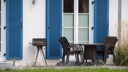 Gartenmöbel und ein Grill stehen auf der Terrasse vor einem Haus