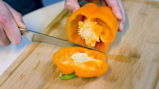 Mann schneidet eine Paprika auf