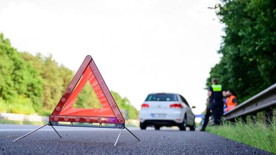 Mit Warndreieck steht nach einer Panne auf der Autobahn