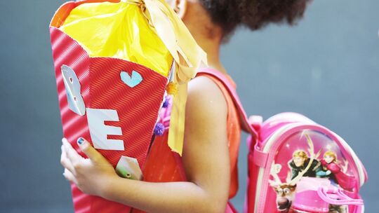Ein Kind hält bei der Einschulung eine Schultüte im Arm