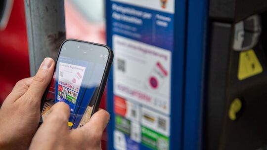 Ein Mann scannt den QR-Code einer Park-App mit einem Smartphone