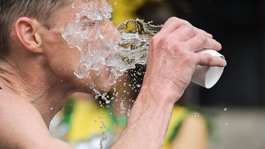 Ein Mann schüttet sich Wasser ins Gesicht