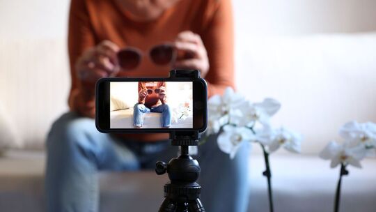 Influencerin folmt sich mit Sonnenbrille in den Händen