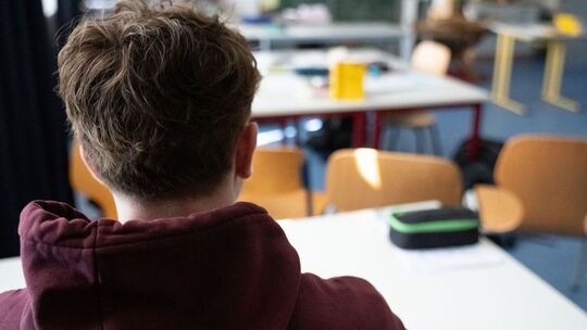 Ein Schüler sitzt an einem Tisch im Klassenzimmer einer Schule