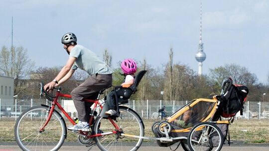 Mann transportiert Kinder mit dem Fahrrad und einem Anhänger