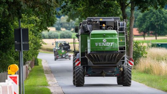 Landwirt fährt mit seinem Mähdrescher auf einer Landstraße