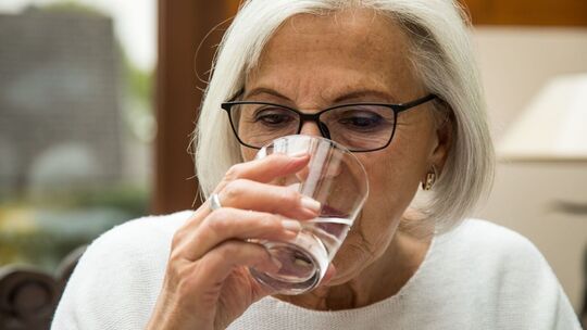 Eine Seniorin trinkt ein Glas Wasser