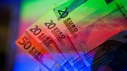 Geldscheine werden von einem Beamer farbig beleuchtet