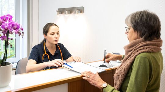 Eine Patientin wird von einer Sprechstundenhilfe beraten