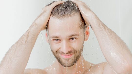 Mann steht unter einer Dusche