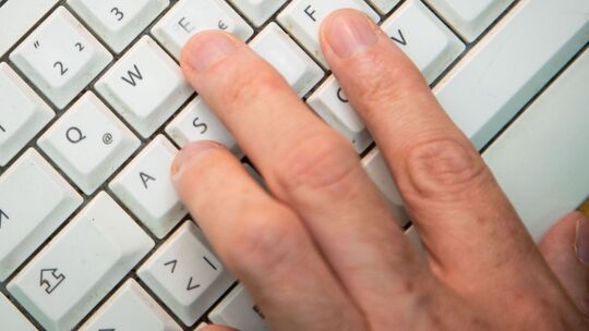 Mann tippt auf einer Tastatur