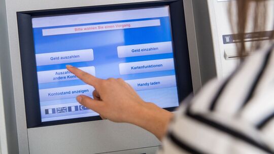 Frau hebt Geld an einem Automaten ab