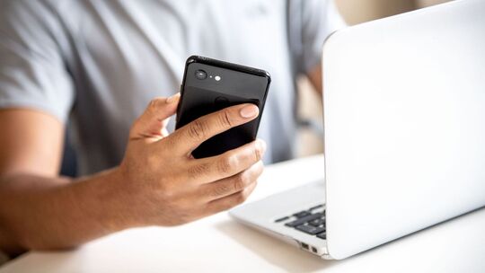 Mann mit Smartphone und Laptop