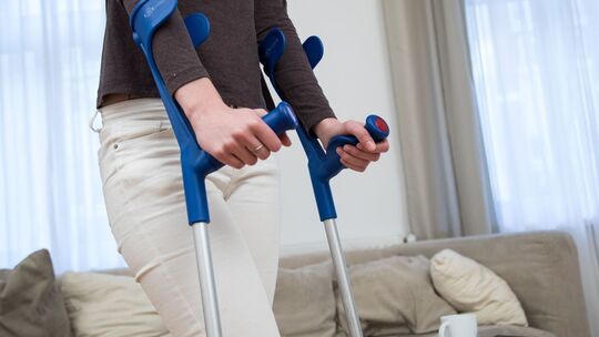 Eine Frau läuft mit Gehhilfen zu Hause
