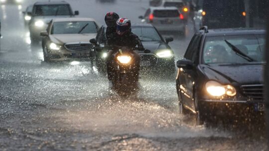 Autos und Motorräder bei Starkregen auf der Straße