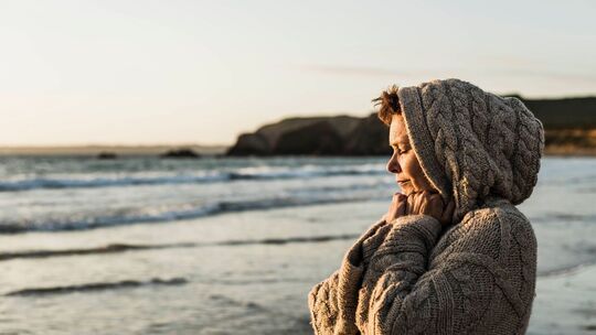 Eine Frau steht bei Sonnenuntergang am Strand