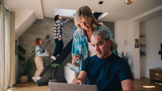 Ein Mann und eine Frau blicken auf einen Laptop