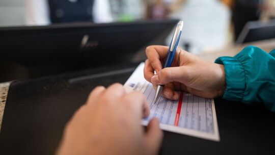 Frau füllt in einem Hotel einen Meldeschein aus