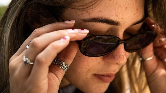 Eine Frau mit Sommersprossen und Sonnenbrille