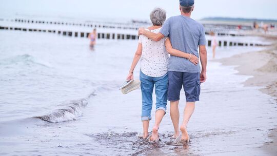 Ein Rentner-Paar spaziert am Strand entlang
