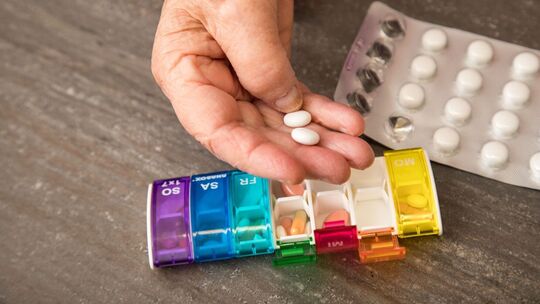 Seniorin nimmt Tabletten aus einer Pillendose
