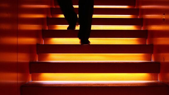 Mann geht eine angeleuchtete Treppe hinab