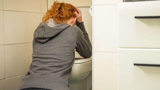 Frau kniet vor einer Toilette