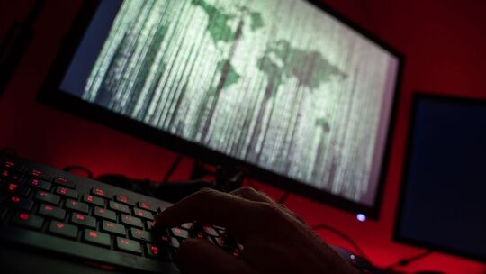 Person sitzt am Rechner und tippt auf einer Tastatur