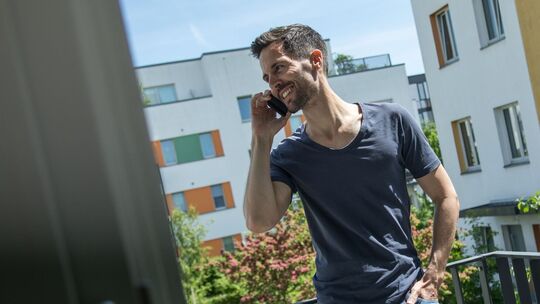 Mann telefoniert auf einem Balkon