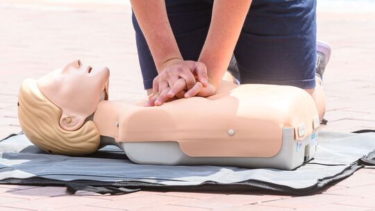 Eine Person übt eine Herzdruckmassage an einer Erste-Hilfe-Puppe