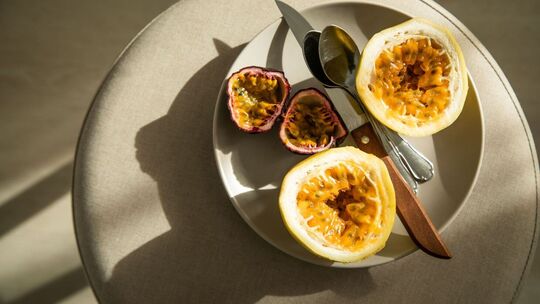 Passionsfrucht (l) und Maracuja liegen auf einem Teller