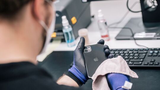 Ein Mitarbeiter überprüft ein refurbished Iphone