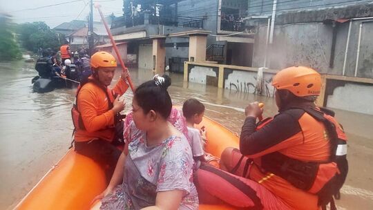 Retter beim Evakuieren bei Überflutungen auf Bali
