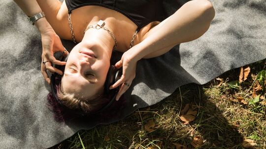 Eine diverse Person mit Kopfhörern im Park