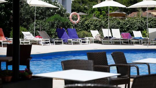 Handtücher liegen auf Sonnenliegen an einem Pool