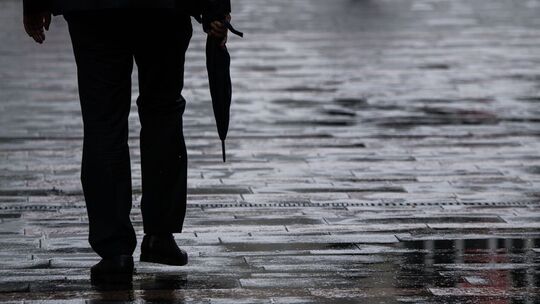 Ein Passant geht mit Regenschirm in der Hand durch Mainz