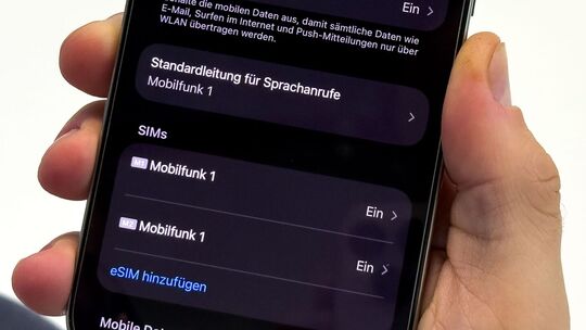 Ein Mann aendert die SIM-Karten-Einstellungen auf einem iPhone